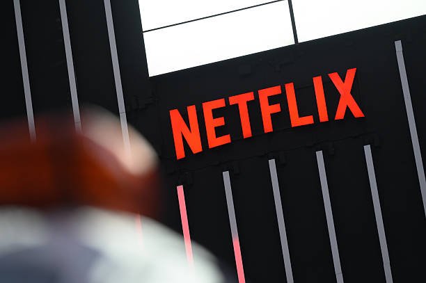 Illuminated Netflix sign mounted on the exterior wall of a building with vertical paneling.